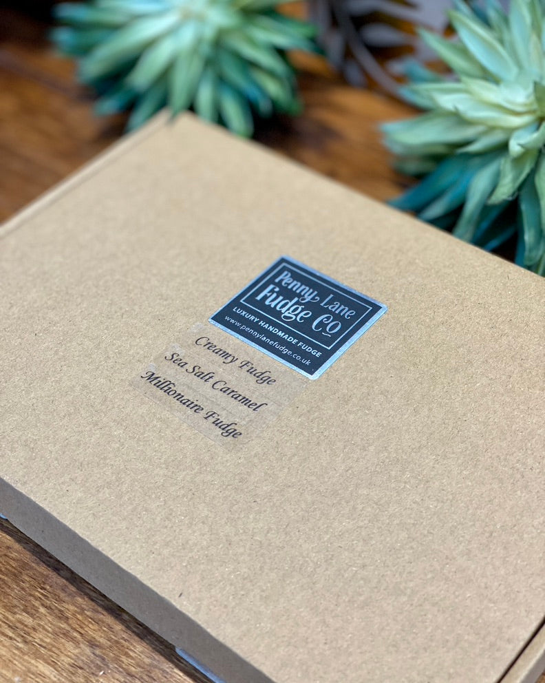 Fudge box with a label on a wooden surface with plants in the background