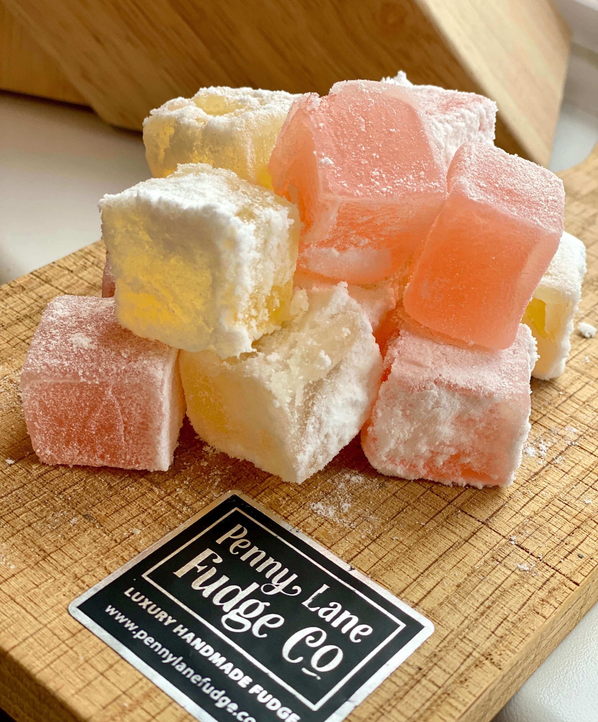 Colorful Rose & Lemon Turkish Delight cubes on a wooden board with Penny Lane Fudge Co label.