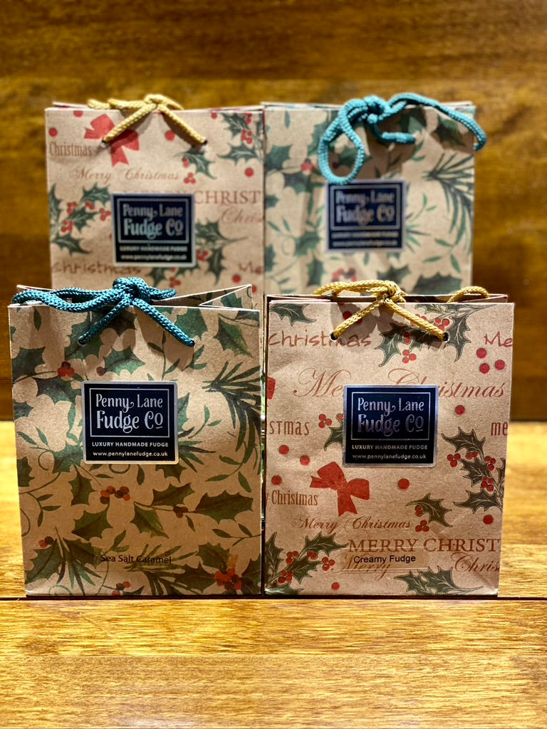 Four small Christmas-themed fudge boxes with decorative patterns on a wooden surface.