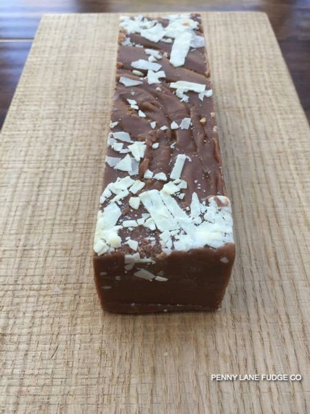 Chocolate fudge bar with white chocolate shavings on a wooden surface, branded 'Penny Lane Fudge Co'.