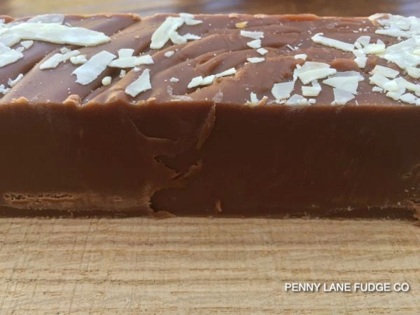 Chocolate fudge bar with white chocolate chips on a wooden surface, branded 'Penny Lane Fudge Co'.