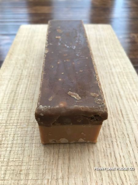 Rectangular caramel fudge bar with a glossy top on a textured surface, branded 'Penny Lane Fudge Co'.