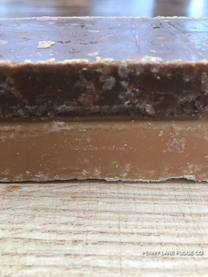 Close-up of a layered caramel fudge bar with visible branding on a textured surface.