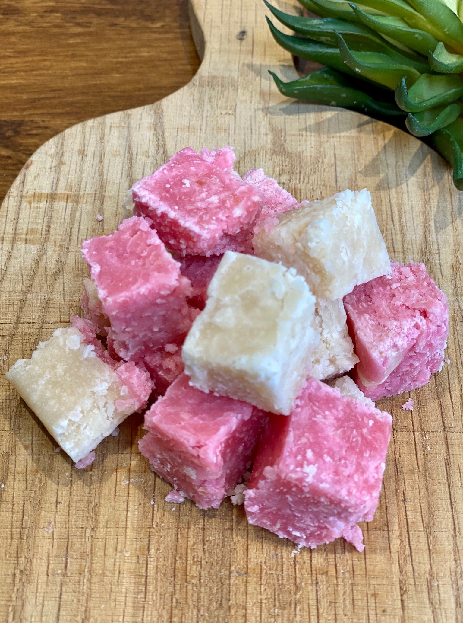 Pink and white layered coconut ice cubes with 'Penny Lane Fudge Co' branding on a wooden surface