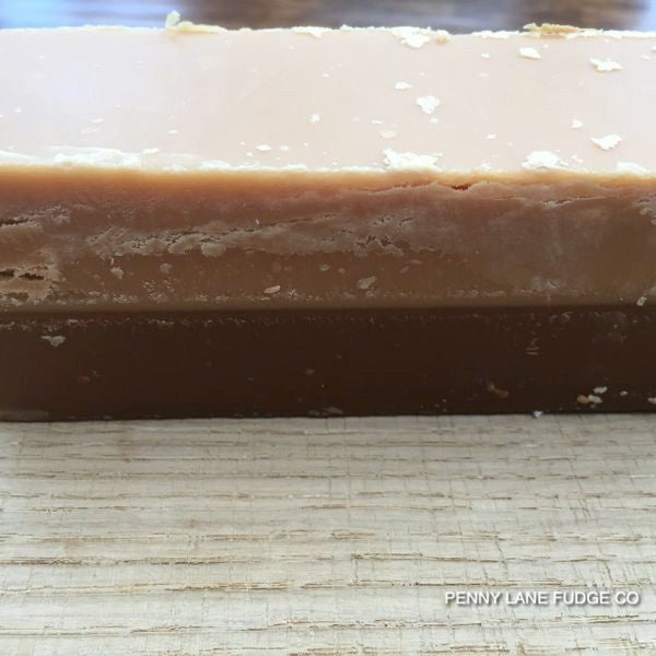 close up of coffe and cream fudge bar stacked on a wooden surface with 'Penny Lane Fudge Co' branding.