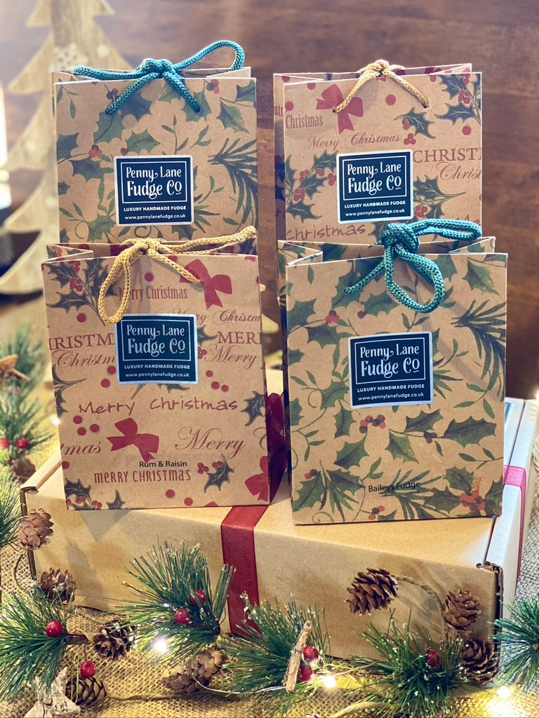Penny Lane Fudge Co gift bags with Christmas designs on a wooden surface.