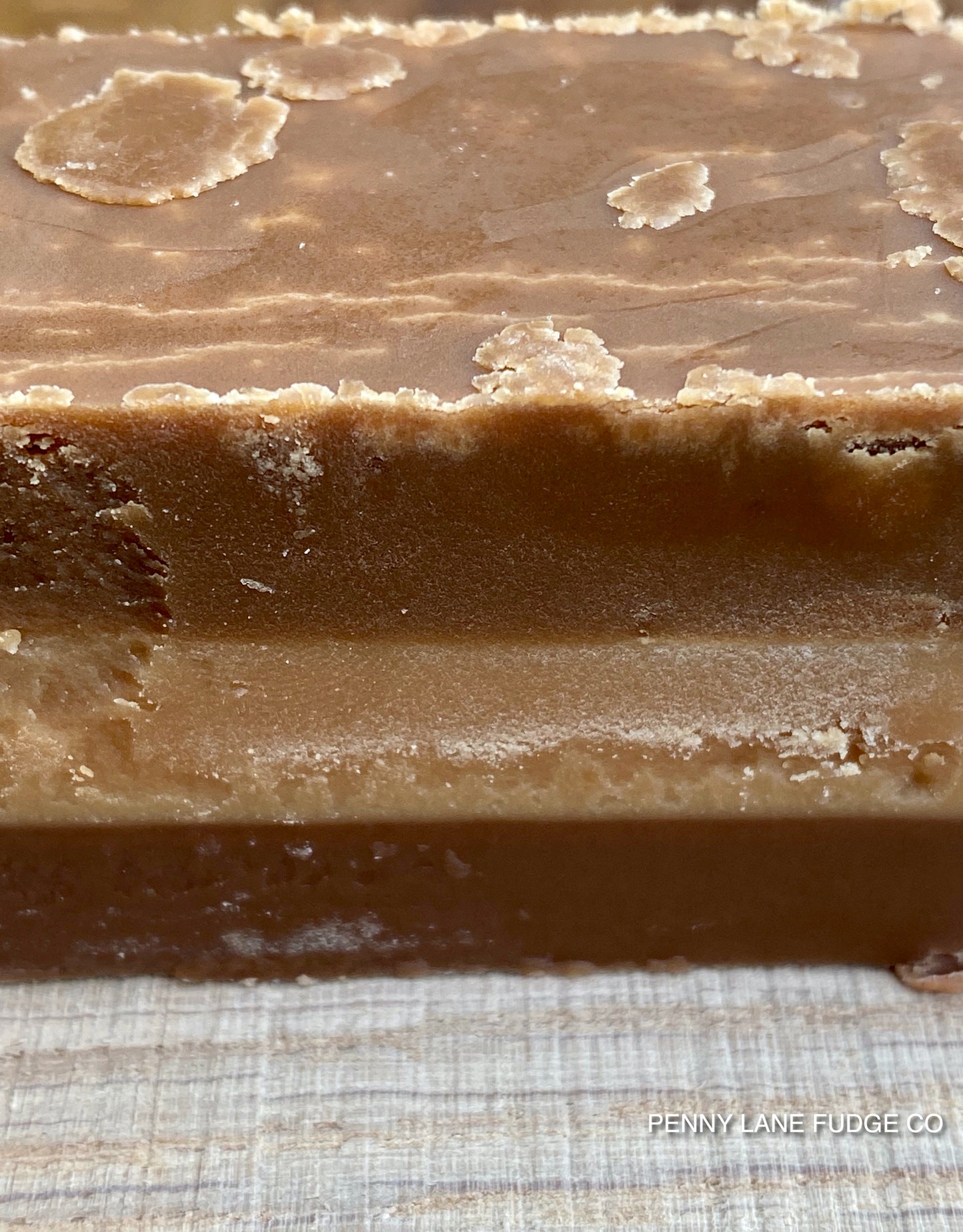 Close-up of a block of millionaire 
fudge with a textured surface on a checkered fabric background.