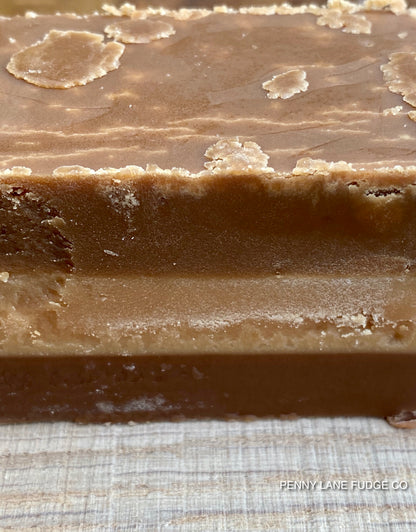 Close-up of a block of millionaire 
fudge with a textured surface on a checkered fabric background.