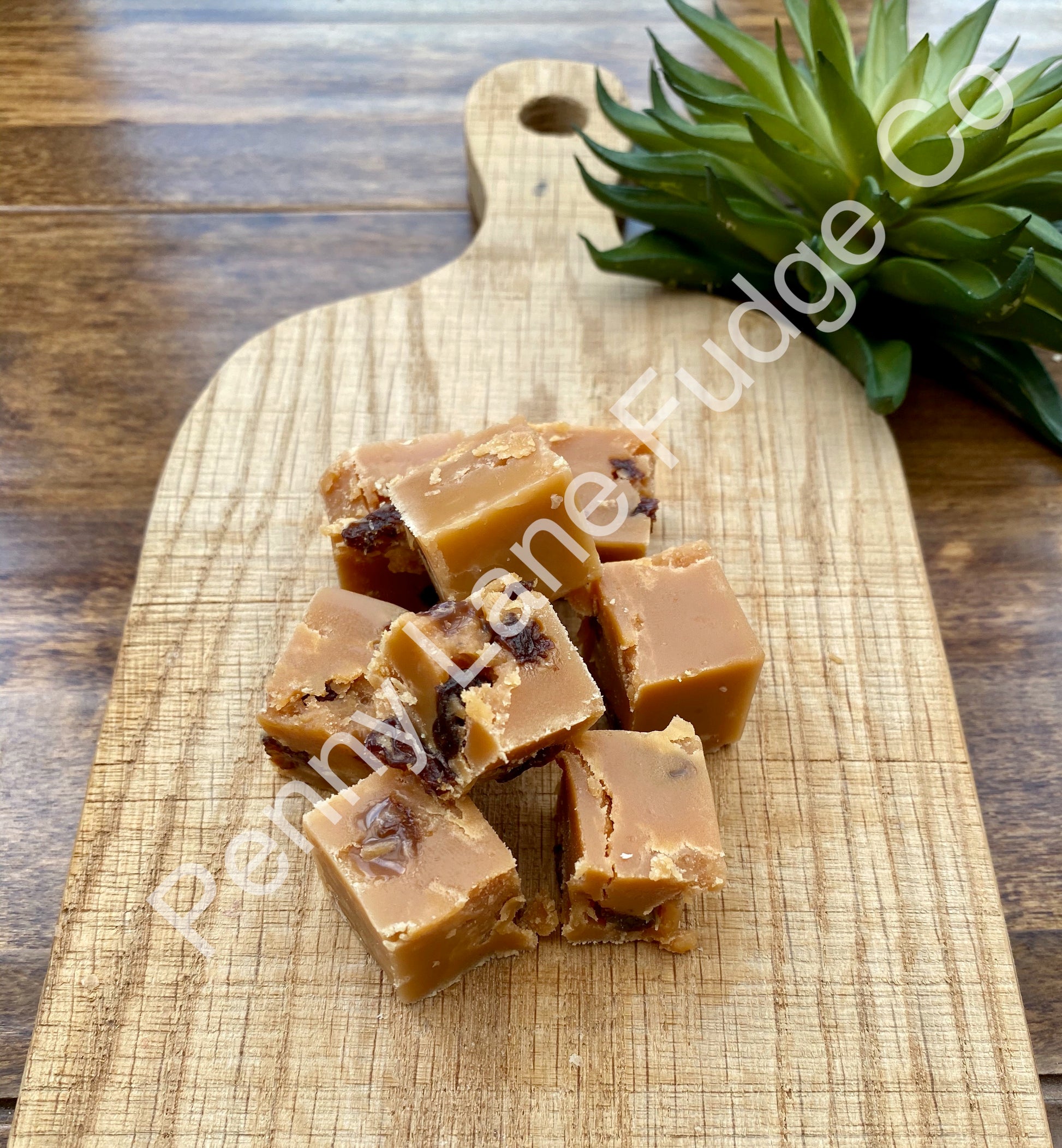 Run & Raisin Fudge on a wooden cutting board, with 'Penny Lane Fudge Co.' branding.