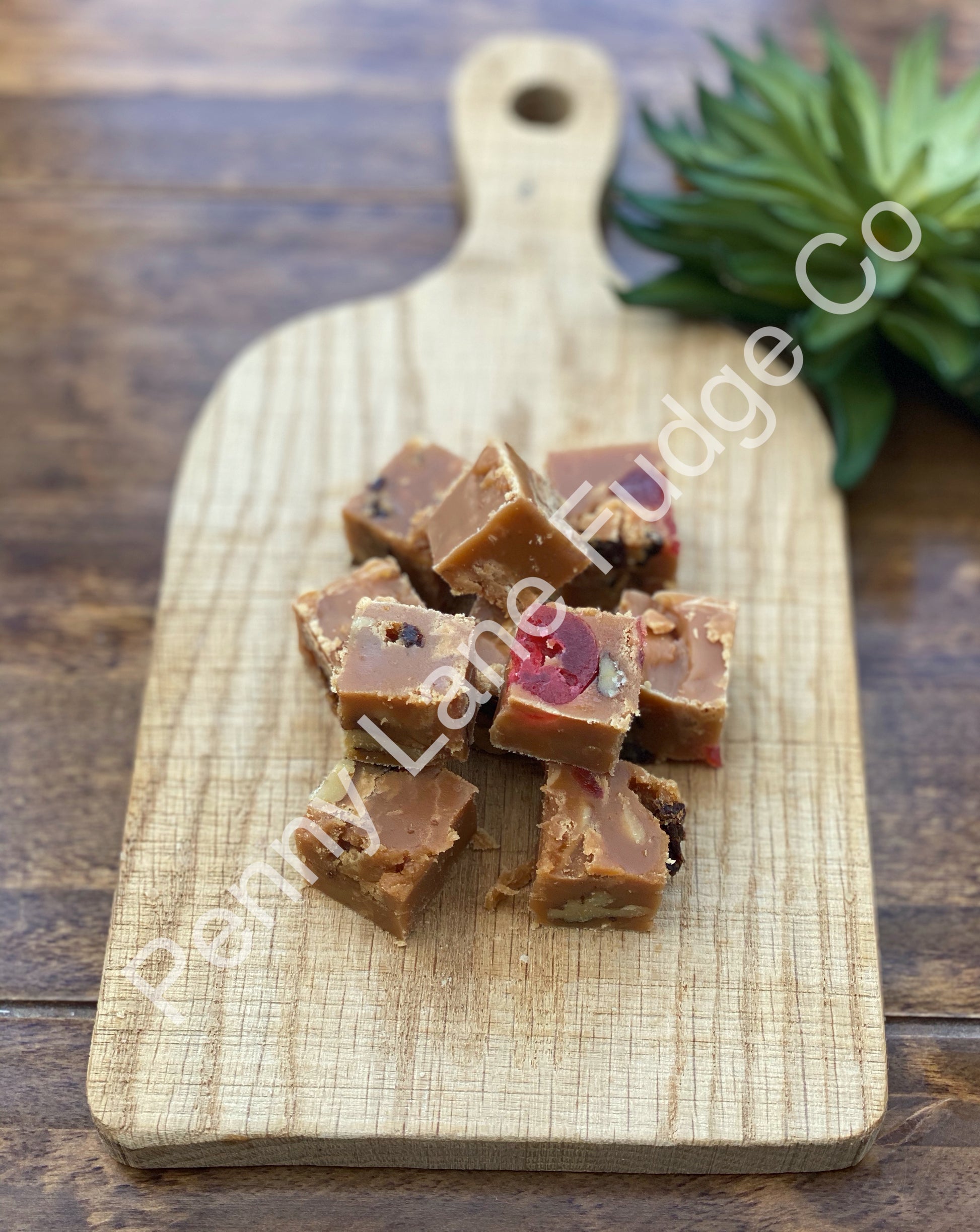 Cubes of fudge on a wooden cutting board with 'Pamela's Fudge Co.' branding.