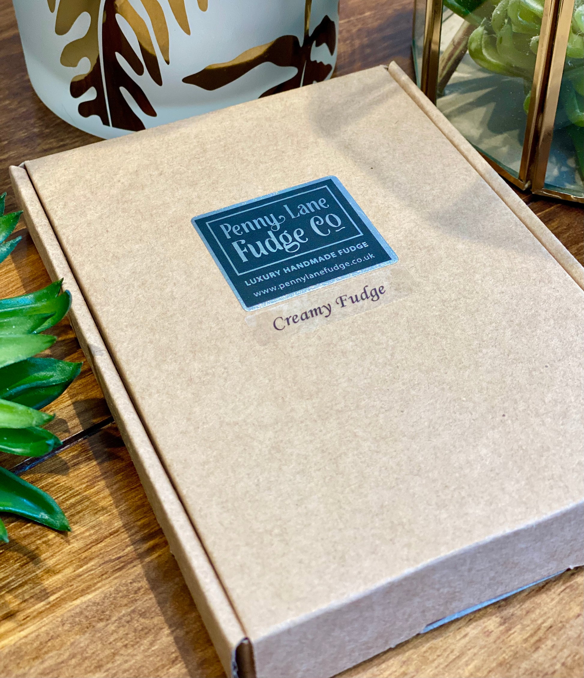Penny Lane Fudge Co. creamy fudge packaging on a wooden surface with a decorative plant.