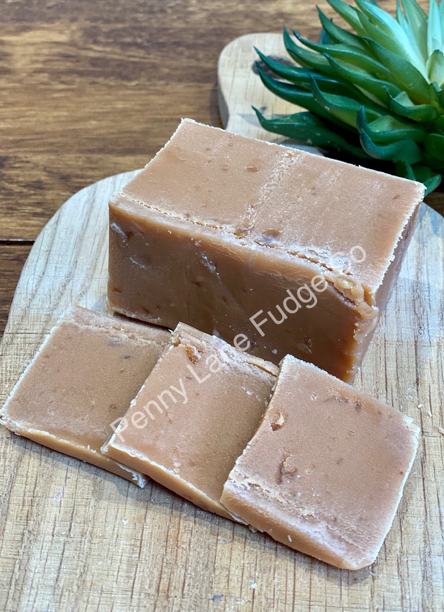 Three slices of stem ginger fudge on a wooden board with a plant in the background, branded 'penny Lane Fudge'.