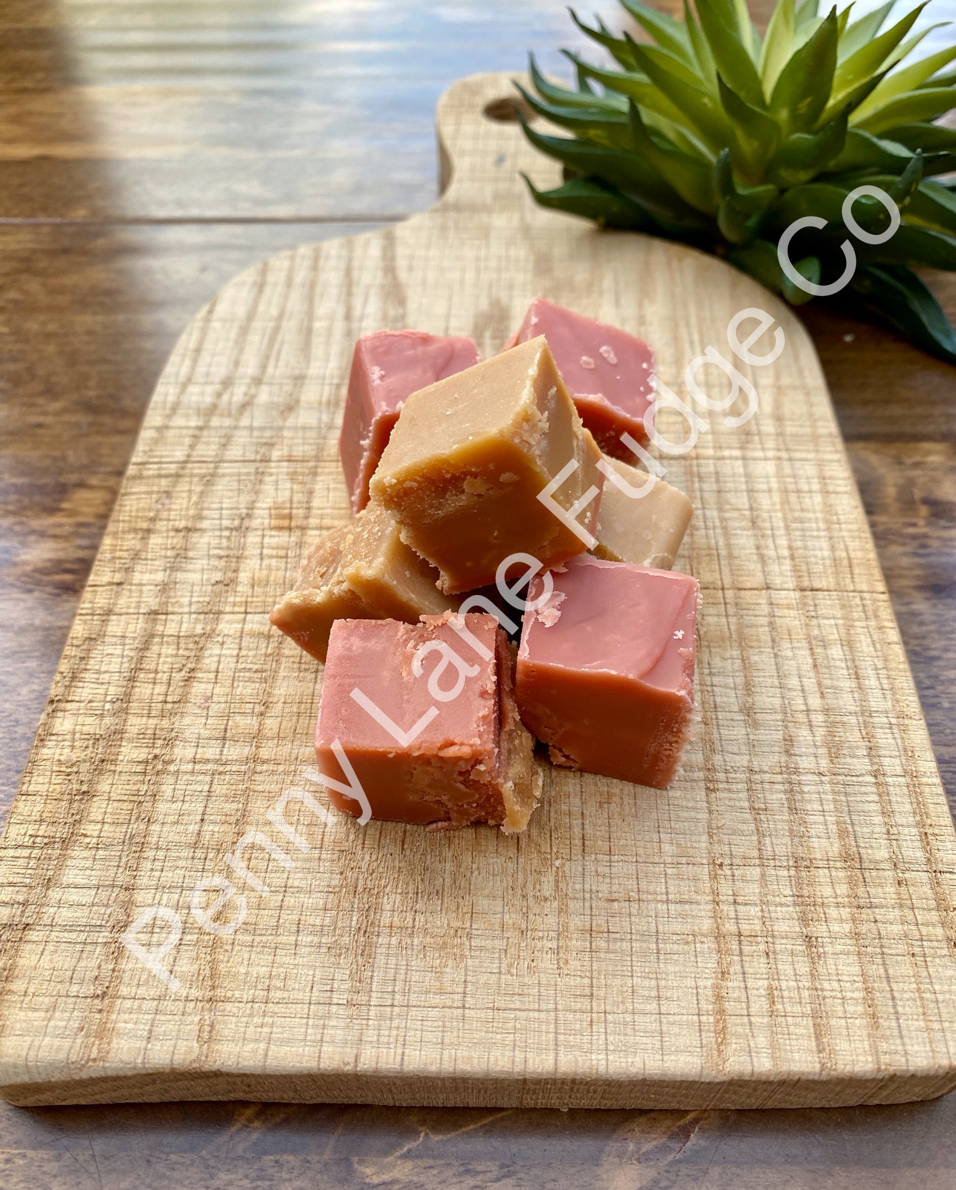 strawberry and cream fudge cubes on a wooden cutting board with 'Penny Lane Fudge Co' branding.