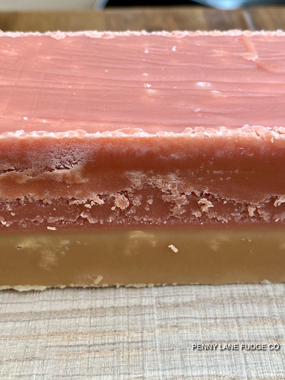 Close-up of a layered fudge bar of sgtrawberry and cream fudge with 'Penny Lane Fudge Co' branding.