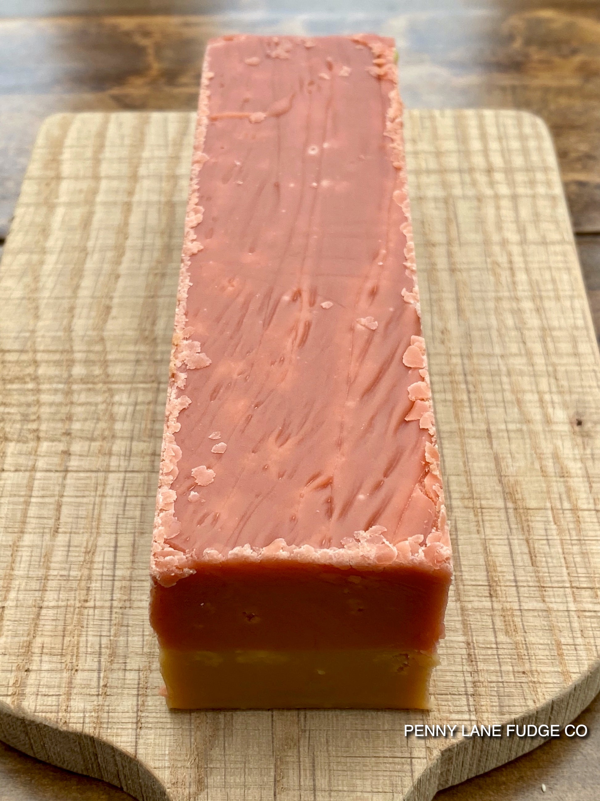 Close-up of a layered fudge bar of sgtrawberry and cream fudge with 'Penny Lane Fudge Co' branding.
