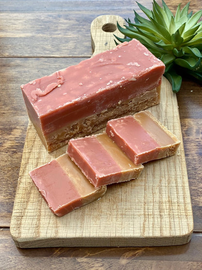 a bar and slices of strawberry and creamfudge,  on a wooden chopping board