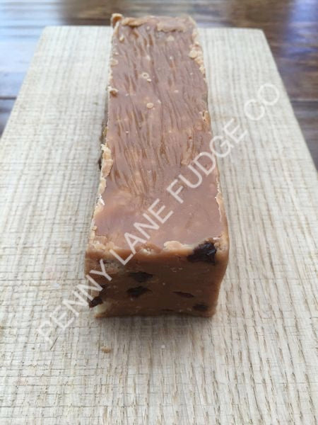 Block of fudge with visible nuts on a textured surface, branded 'Jenny Lane Fudge Co'.