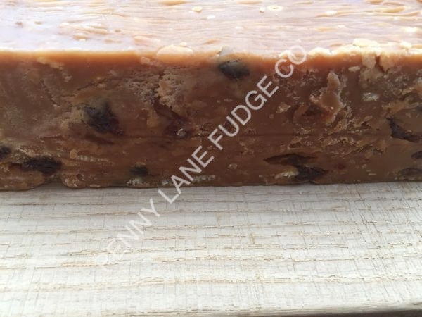 Close-up of a block of fruit and nut fudge with raisins on a textured surface, featuring the brand 'Elfiny Lane Fudge Co'.
