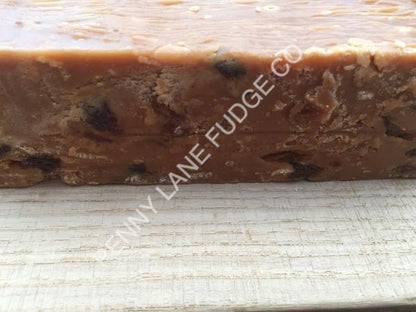 Close-up of a block of fruit and nut fudge with raisins on a textured surface, featuring the brand 'Elfiny Lane Fudge Co'.