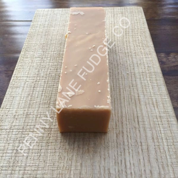 block of peanut butter fudge with 'Penny Lane Fudge Co' branding on a wooden surface.