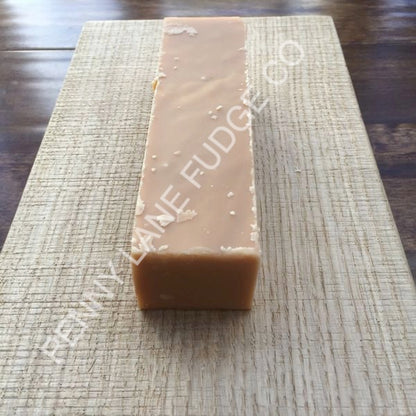 block of peanut butter fudge with 'Penny Lane Fudge Co' branding on a wooden surface.
