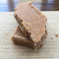 Three pieces ofcrumbly scottish tablet on a textured surface